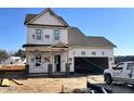 Two story home under construction featuring a garage, covered porch, and dark shingle roof set against a clear blue sky at 243 Danube Dr, Zebulon, NC 27597