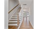 Open concept hallway and staircase with hardwood floors and white walls leading to living area at 545 Eversden Dr, Zebulon, NC 27597