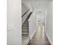Inviting hallway with hardwood floors, a carpeted staircase, and ample natural light streaming through the open doorway at 556 Eversden Dr, Zebulon, NC 27597