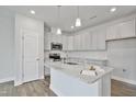 Modern kitchen featuring white cabinets, granite countertops, stainless appliances, and a center island with pendant lighting at 556 Eversden Dr, Zebulon, NC 27597