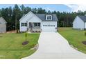 New home with a well-manicured lawn, a two-car garage, gray siding, and a beautiful blue sky at 95 Purslane Dr, Franklinton, NC 27525