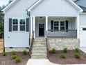 Inviting front porch with stone stairs, a wood railing, black door, and manicured landscaping at 95 Purslane Dr, Franklinton, NC 27525