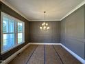 Formal dining room featuring custom wall paneling, large window, and elegant chandelier at 190 Broadleaf Ln, Youngsville, NC 27596
