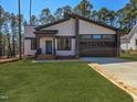 Landscaped front yard featuring a modern two-story home with gray-toned siding, black trim and a concrete driveway at 2662 Sledge Rd, Louisburg, NC 27549
