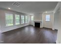 Spacious living room with dark wood floors, fireplace, and large windows with natural light at 1528 Goldfinch Perch Ln, Knightdale, NC 27545