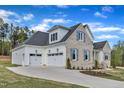 Three car garage elevation with white garage doors, light-colored brick and clean landscaping at 3803 Bennett Grove Dr, Wake Forest, NC 27587
