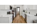 Modern kitchen with white cabinets, quartz countertops, and stainless steel appliances at 438 S Hillsborough St, Franklinton, NC 27525