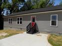 Rear exterior view of the home with gray siding, a red door, and a concrete patio at 104 Halifax Rd, Louisburg, NC 27549
