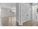 Hallway with hardwood floors and white doors, leading to laundry and living space at 1177 St. Cloud Loop, Apex, NC 27523