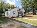 Charming, painted brick home with covered front porch and well-manicured lawn on a sunny day at 1302 E Jones St, Raleigh, NC 27610