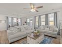 A bright living room with hardwood floors, neutral colored couches, decorative pillows, and large windows with curtains at 168 Begonia St, Angier, NC 27501