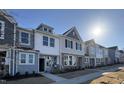 View of newly-constructed townhomes with varying architectural styles under a bright blue sky at 6336 Granite Quarry Dr, Raleigh, NC 27610