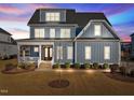 Stunning two-story home with gray siding, white trim, and a landscaped lawn at dusk at 1188 Duke Farm Dr, Wake Forest, NC 27587