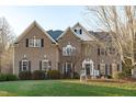 Two story brick home with landscaping and large tree in front at 7828 Percussion Dr, Apex, NC 27539