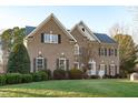 Two story brick home with landscaping and large tree in front at 7828 Percussion Dr, Apex, NC 27539