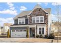 Two-story home with stone and shingle accents, two-car garage, and landscaping at 1109 Timbercut Dr, Durham, NC 27703