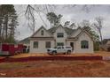 Two-story white brick home with black framed windows and dark roof, set in a wooded area undergoing construction at 6805 Greystone Dr, Raleigh, NC 27615