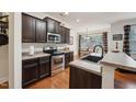 Well-lit kitchen with stainless steel appliances, dark cabinets and wood flooring at 320 Westgrove Ct, Durham, NC 27703