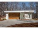 Contemporary home showcasing a modern wood garage door and minimalist design with a concrete driveway at 6358 Pathway Ct Ct, Chapel Hill, NC 27516