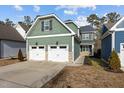 Two-story house with green siding, two-car garage, and a landscaped yard at 104 Spruce Hollow Cir, Spring Lake, NC 28390