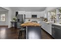 Open kitchen featuring white cabinetry, stainless steel refrigerator, eat-in butcher block island, and modern appliances at 205 Spring St, Louisburg, NC 27549