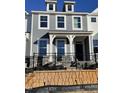 A modern, two-story townhome with a charming gray exterior, white trim, and a secure black metal fence at 498 Traditions Grande Blvd # 23, Wake Forest, NC 27587