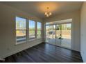 Bright dining area with dark hardwood floors, three windows, and access to the patio at 500 Traditions Grande Blvd # 22, Wake Forest, NC 27587
