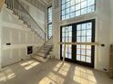Sunlit foyer featuring a staircase, soaring windows, and a door that leads to outdoor space at 7013 Buckhead Dr, Raleigh, NC 27615