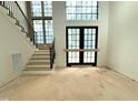 Unfinished living room features large black framed windows and doors, a staircase, and neutral walls at 7013 Buckhead Dr, Raleigh, NC 27615