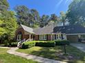 Attractive brick home with manicured front lawn and shrubs, carport, and classic design elements under a clear blue sky at 1210 Huntsman Dr, Durham, NC 27713
