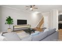 Virtually staged living room with hardwood floors, a modern couch and a large TV at 2225 Raven Rd # 107, Raleigh, NC 27614