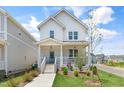 Inviting two-story home with a quaint front porch, featuring a light blue door and landscaped yard at 129 Mossy Falls Way, Wendell, NC 27591
