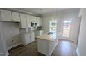 New kitchen with white cabinets, an island, stainless appliances, and hardwood floors at 203 Broomgrove Way, Wake Forest, NC 27587