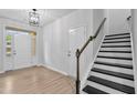 Bright foyer featuring hardwood floors and staircase with wooden railing and contrasting black treads at 2094 Harris Farm Ct, Burlington, NC 27215