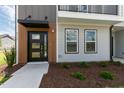 Home exterior showcasing modern entry door, black accents, complemented by professionally landscaped grounds at 2117 Treelight Way, Wendell, NC 27591