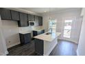 Stylish kitchen features a center island with a sink, black cabinetry and stainless steel appliances at 205 Broomgrove Way, Wake Forest, NC 27587