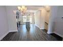 Open-concept living space featuring hardwood floors, a modern chandelier, and kitchen view at 205 Broomgrove Way, Wake Forest, NC 27587