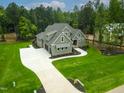 Aerial view showcasing a home with a large driveway, lush lawn, surrounded by dense trees at 3913 Cedar Knolls # 7, Youngsville, NC 27596