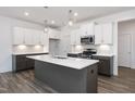 Modern kitchen featuring white cabinets, gray island with quartz countertop, stainless appliances, and stylish pendant lighting at 3935 Willow Gate Way, Knightdale, NC 27604