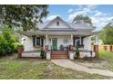 Charming white home featuring a welcoming front porch with brick columns, a green door, and well-maintained landscaping at 1006 W Broad St, Dunn, NC 28334