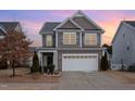 Two-story house with a neutral color scheme and a two-car garage, at dusk at 1122 Tulip Poplar Rd, Fuquay Varina, NC 27526