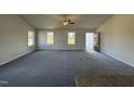 Bright living room with grey carpet, neutral walls, and multiple windows at 75 Shiloh Dr, Lillington, NC 27546