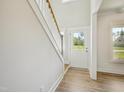 Bright entryway featuring wood flooring, a staircase with white risers and a partial view to the outside at 18 Hewitt Woods Dr, Clayton, NC 27527