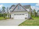 Two-story home with a spacious two-car garage, gray accents, and a well-manicured lawn and stone accents at 18 Hewitt Woods Dr, Clayton, NC 27527