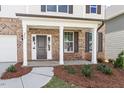 Inviting front porch with brick accents, white columns, a dark front door, and landscaped garden bed at 257 North Maple Walk Dr # 218, Garner, NC 27529