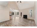 Open living room featuring a fireplace, vaulted ceilings, and hardwood floors that connects to the breakfast nook and kitchen at 316 Trafalgar Ln, Cary, NC 27513