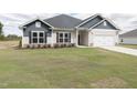 New construction home with a two-tone exterior, landscaped lawn, and driveway at 572 Glenkirk Pl, Garner, NC 27529