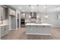 Modern kitchen with stainless steel appliances, an island, pendant lights, and wood-look flooring at 102 Belmont Stakes Ln, Wendell, NC 27591