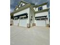Exterior showcasing a three car garage with stylish pergola and concrete driveway at 1229 Azalea Garden Cir, Raleigh, NC 27603