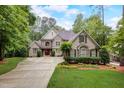 Elegant stone home featuring lush landscaping, a long driveway, and a welcoming red front door at 1300 Caistor Ln, Raleigh, NC 27614